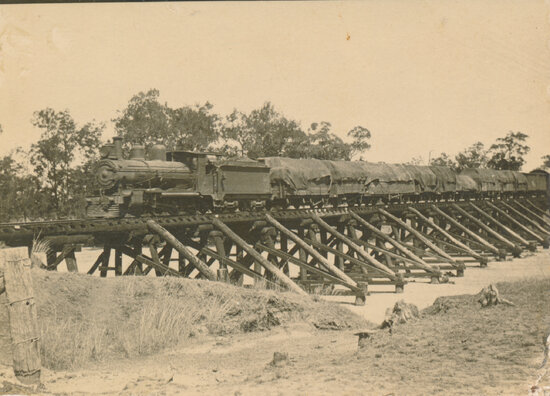Steam train crossing low level timber bridge, Macrossan