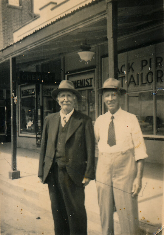 Robert Carson and Jack Pirie in front of Jack Pirie Tailor shop and W Griffiths Pharmacy, Gill Street