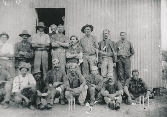 Miners in front of a tin shed with candles