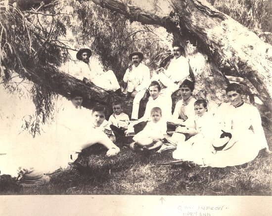 Group of men, women and children under a tree