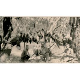 A party of duck shooters beside a creek with their kill on rope line