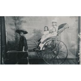 Studio portrait of Mother and two daughters sitting in a Rickshaw pulled by a Chinese child