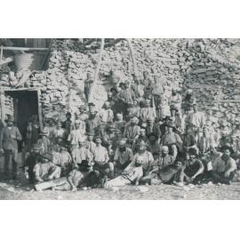 Miners in front of stone clad mine shaft entrance