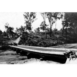 Low level timber bridge across wide creek with car