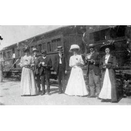 Group standing beside Train holding cups of Tea
