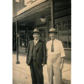 Robert Carson and Jack Pirie in front of Jack Pirie Tailor shop and W Griffiths Pharmacy, Gill Street