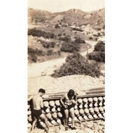 Two men in swimming trunks beside rack of bombs, Replenishment Centre, Towers Hill 1940s