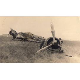 Four men standing with a crashed plane in a field, wing propeller torn off
