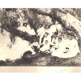 Group of men, women and children under a tree