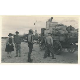 Gladys Chappel with actors Simon Burke & Michael Craig watching a wagon get loaded on the set of ‘The Irishman’ movie, Dalrymple Saleyards 1977
