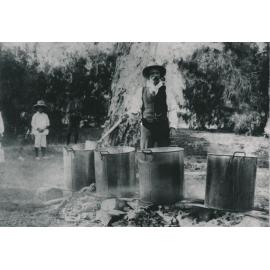 Man standing over large boiling pots beside River