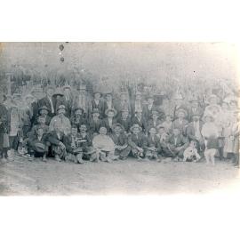 Large group of people in front of a bough shelter